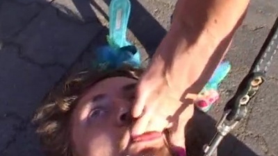 Leashed slave licking mistresses bare feet after a pony play outdoors